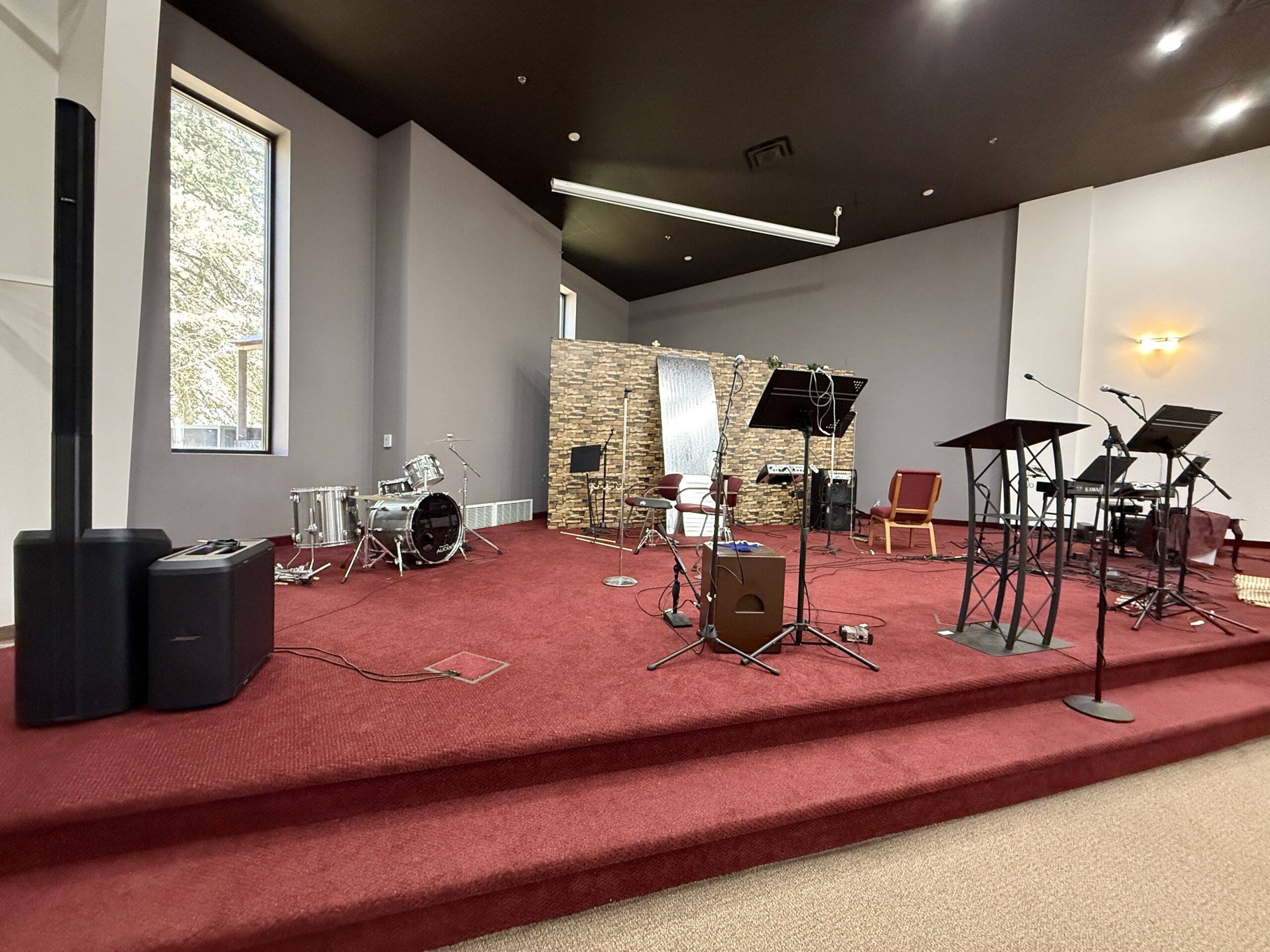 Church painting sanctuary interior painting — warm gray walls, dark painted ceiling, red carpeted stage (Speese Painting)