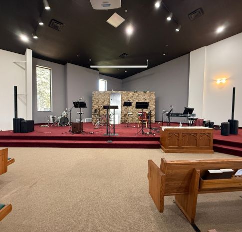 Church painting Grand Rapids — renovated sanctuary stage with black ceiling, gray accent walls, and stone backdrop at Revolution Point Church