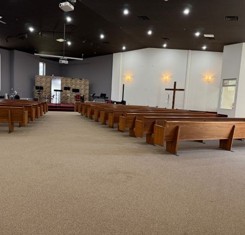 Church painting Grand Rapids — center-aisle view of updated sanctuary with black ceiling, neutral walls, and polished pews