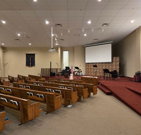 Church painting Grand Rapids – sanctuary before restoration with pews, projector, and high white ceiling at Revolution Point Church