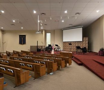 Church painting Grand Rapids – sanctuary before restoration with pews, projector, and high white ceiling at Revolution Point Church