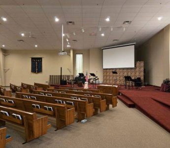 Church painting Grand Rapids – sanctuary before restoration with pews, projector, and high white ceiling at Revolution Point Church